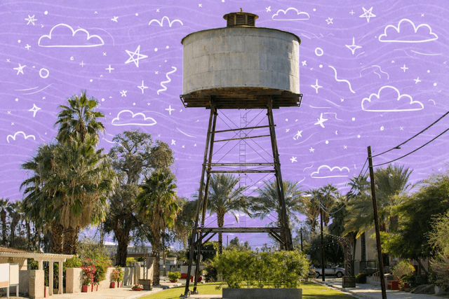 Historic metal water tower surrounded by palm trees and desert landscaping in Indio, California neighborhood park
