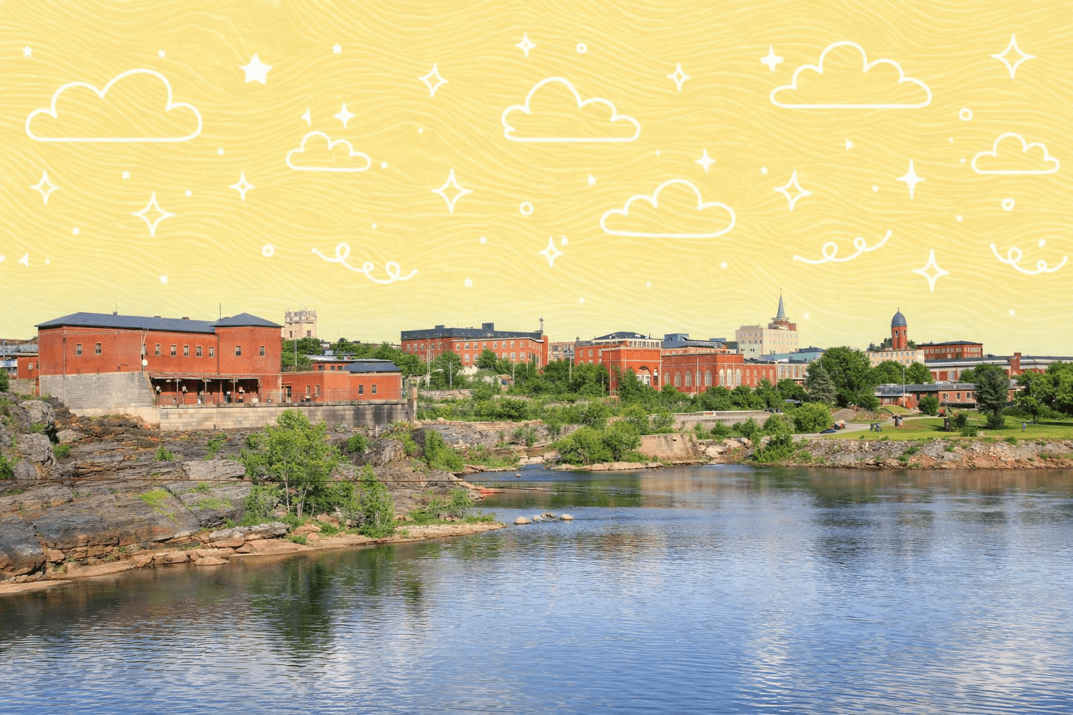 Scenic view of Lewiston, Maine's riverside with historic brick buildings and blue sky.