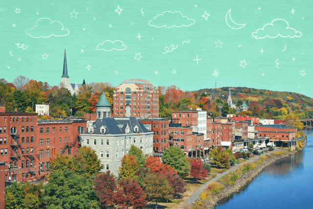 Scenic view of downtown Augusta, ME with historical buildings and vibrant fall foliage along the river.