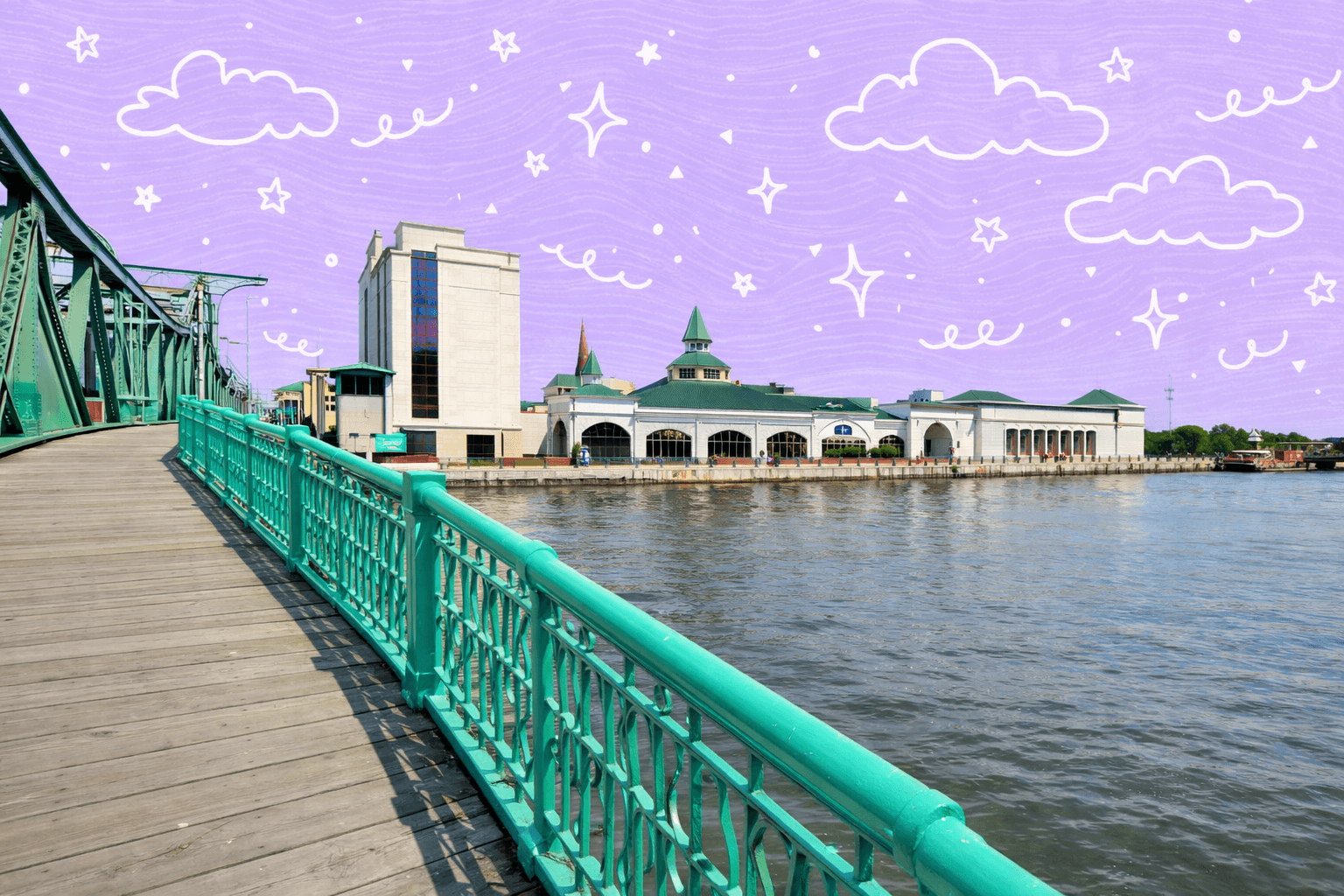 Pedestrian bridge leading to buildings by the river in Joliet, Illinois under a clear blue sky.