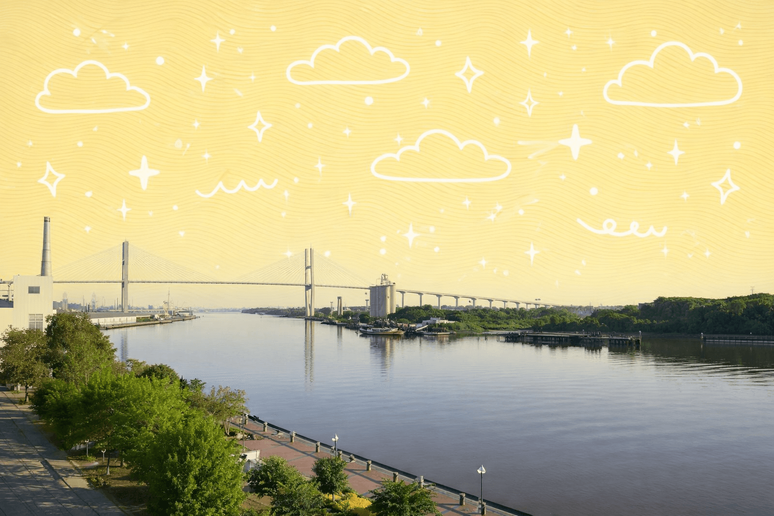 View of the Talmadge Bridge across the Savannah River in Savannah, Georgia with clear skies and trees in the foreground.
