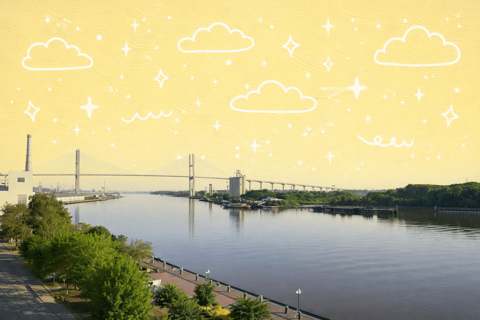 View of the Talmadge Bridge across the Savannah River in Savannah, Georgia with clear skies and trees in the foreground.