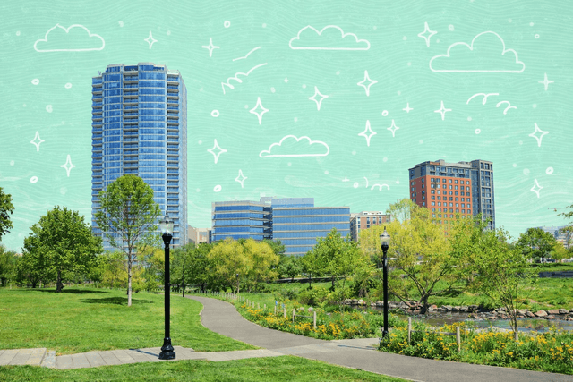Scenic view of a park with trees and pathways leading to modern skyscrapers in Stamford, CT, under a clear blue sky.